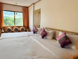 een slaapkamer met een groot bed met paarse en witte kussens bij Takiab Beach Resort in Hua Hin +27 foto's