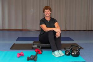 Een vrouw zit op een pilatesmat met haar apparatuur. bij B en B Gewoon Doen Groede in Groede
