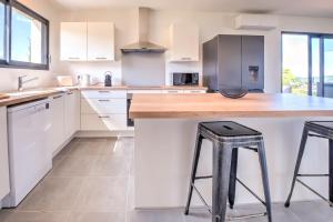 una cucina con armadi bianchi e un bancone con due sgabelli da bar di Sunset villa a Trélissac