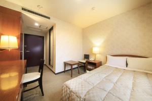 a hotel room with a large bed and a desk at Shinmatsudo Station Hotel in Matsudo