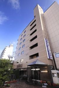 a tall building with an umbrella in front of it at Shinmatsudo Station Hotel in Matsudo