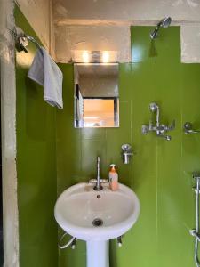 a green bathroom with a sink and a mirror at Sunny Side Up top-floor apartment in Kathmandu +14 photos