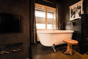 a bath tub in a bathroom with a window and a stool at Hotel Huis van Bewaring - Bijzonder boutique hotel in historisch pand in Almelo +92 photos