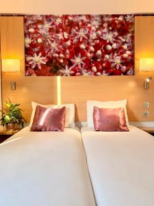 two beds in a room with a painting on the wall at Fasthotel Orleans Zénith in Orléans