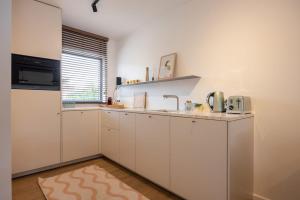 a kitchen with white cabinets and a sink at Hello Zeeland - De Brabander Wijk 111 in Cadzand