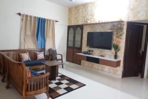 a living room with a tv and a couch at Thiruveesar Family Retreat near Airport in Tiruchirappalli