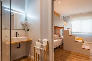 a bathroom with a sink and a bedroom at White Tree Rooms and Apartments in O Pedrouzo +37 photos