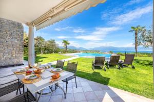 a patio with a table and chairs and a pool at Villa Perla by Whale Homes in Lonato