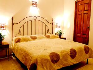 a bedroom with a large bed with a yellow blanket at Hotel Dainzu in Oaxaca City