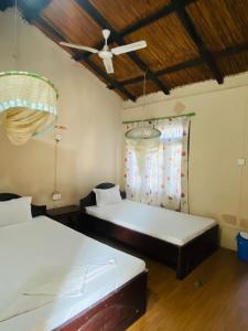 a bedroom with two beds and a ceiling fan at Annapurna View Lodge in Chitwan