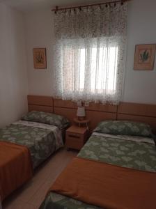 a bedroom with two beds and a window at Apartamentos Marina d'or in El Borseral +24 photos