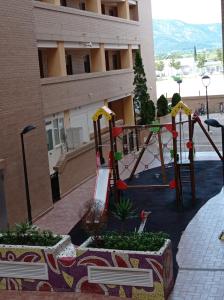 a playground in front of a building with a swing at Apartamentos Marina d'or in El Borseral