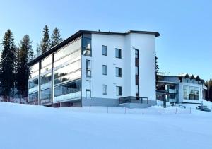 a white building with snow in front of it at Ski-Inn Huoneisto in Vuokatti