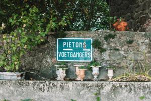 a sign on a stone wall with potted plants at Les Meules in Saint-Basile