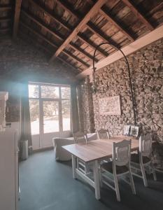 a room with a table and chairs and a stone wall at Les Meules in Saint-Basile