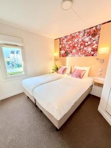 een slaapkamer met een groot bed met een schilderij aan de muur bij Fasthotel Orleans Zénith in Orléans +28 foto's