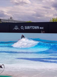 een man die op een surfplank in de oceaan op een golf rijdt bij Hampton by Hilton Munich Airport South in Hallbergmoos +147 foto's