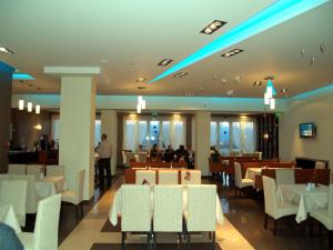 a dining room with white tables and white chairs at Ioannou Resort in Ptolemaida