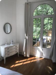 een slaapkamer met een dressoir en een groot raam bij L'isenbart, appartement de charme et central in Besançon