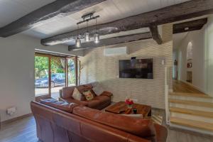 een woonkamer met een leren bank en een tv bij Le ruisseau du bejean in Sainte-Gemme