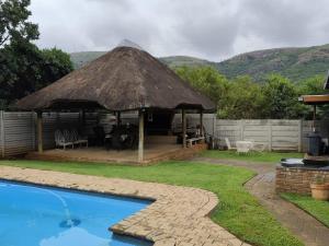 a gazebo with a grass roof next to a pool at 899 On Burlington in Pretoria