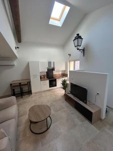 a living room with a couch and a tv at La maison du Quart - Maison de village in Sommières