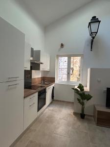 a kitchen with white cabinets and a window at La maison du Quart - Maison de village in Sommières