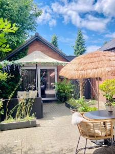a patio with a table and a straw umbrella at Het Roerhofje in Herkenbosch