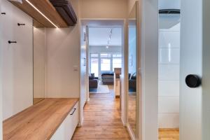 een gang die leidt naar een woonkamer met witte kasten en houten vloeren bij Alte Teestube in Norderney +15 foto's