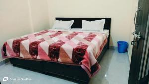 a bedroom with a bed with a red and white blanket at Hotel Aarav Inn in Pānīpat