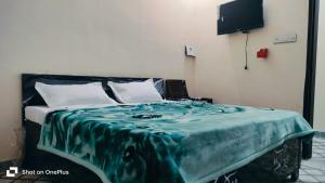a bedroom with a bed with a green blanket on it at Hotel Aarav Inn in Pānīpat +7 photos