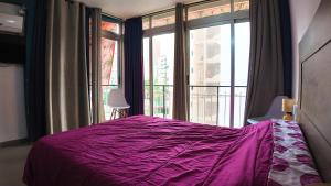 una camera con un letto viola e una grande finestra di Apartalux Vera Rincón de Loix a Benidorm