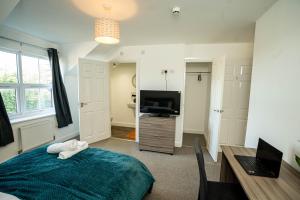 a bedroom with a bed and a desk and a television at Queens Court Ensuite Studio in Stoke on Trent