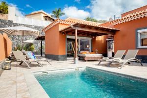 a patio with a pool and chairs and a house at Villa Cornelia in Adeje