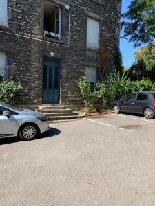 twee auto's geparkeerd op een parkeerplaats voor een gebouw bij Le Nid, petit studio cosy et central in Besançon