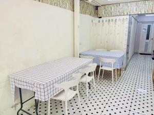 two tables and chairs in a room with white tiles at BKK Rama3 Guest House in Bangkok +22 photos