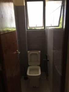 a small bathroom with a toilet and two windows at Jowi homes in Mtwapa