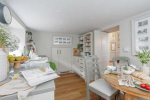 a kitchen with white cabinets and a wooden table at Olive Cottage in Swanage