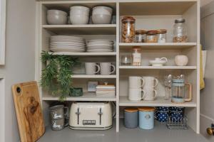 a cupboard filled with plates and other items at Olive Cottage in Swanage +15 photos