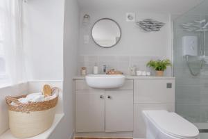 a bathroom with a sink and a toilet and a mirror at Olive Cottage in Swanage
