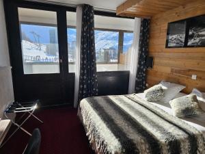 a hotel room with a bed and a window at Hotel Le Pelvoux in Les Menuires