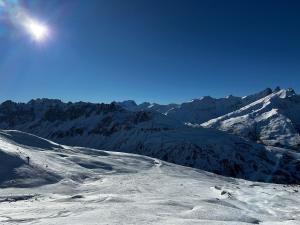 a snow covered mountain with the sun in the sky at Cosy Suite chalet in Valloire
