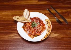 a plate of pasta and bread on a table at The Orion Elite - Green Park in New Delhi