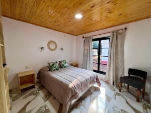 a bedroom with a bed and a window and a chair at Cabañas Rincón Andaluz in Puerto Iguazú +17 photos