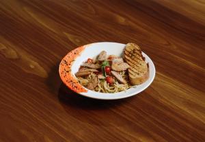 a bowl of noodles and meat and bread on a table at The Orion Elite - Green Park in New Delhi +105 photos