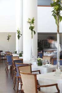 een eetkamer met tafels en stoelen met bloemen in vazen bij Hotel Escola in Funchal
