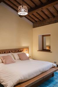 a bedroom with a large white bed with a wooden headboard at Le Dimore by Borgo Tessile - Feronia in Orvieto