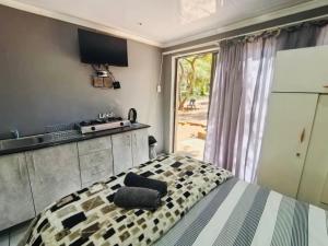a bedroom with a bed and a kitchen with a window at Kameeldoring Guesthouse in Zeerust