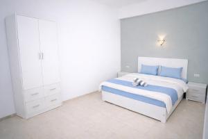 a white bedroom with a bed with two shoes on it at Astralis Hotel - Hot Air Balloon View in Al Aqālitah +13 photos