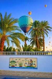 a hot air balloon flying over a wall with palm trees at Astralis Hotel - Hot Air Balloon View in Al Aqālitah